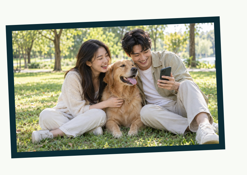 Two pet owners sharing a pet report in a sunny park beside a golden retriever